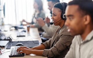 A team of professionals providing IT Support, wearing headsets and working on computers in a modern office environment.